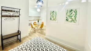 A modern kitchen with white cabinets, a dining table with yellow chairs, and a hanging light fixture. - China Town Madrid 02 (1-bedroom apartment) (Madrid)