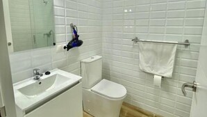 A bathroom with white tiles, a sink, a toilet, and a mirror. - China Town Madrid 02 (1-bedroom apartment) (Madrid)