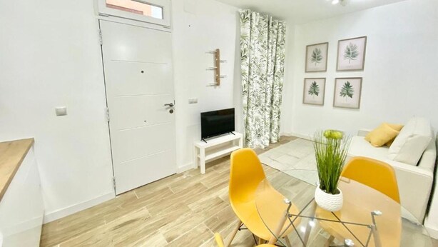 A compact living space with a dining area, a sofa, a TV, and a door with a window. - China Town Madrid 02 (1-bedroom apartment) (Madrid)