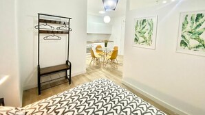 A hallway with a hanging light fixture, a coat rack, a patterned rug, and two framed artworks on the wall. - China Town Madrid 02 (1-bedroom apartment) (Madrid)