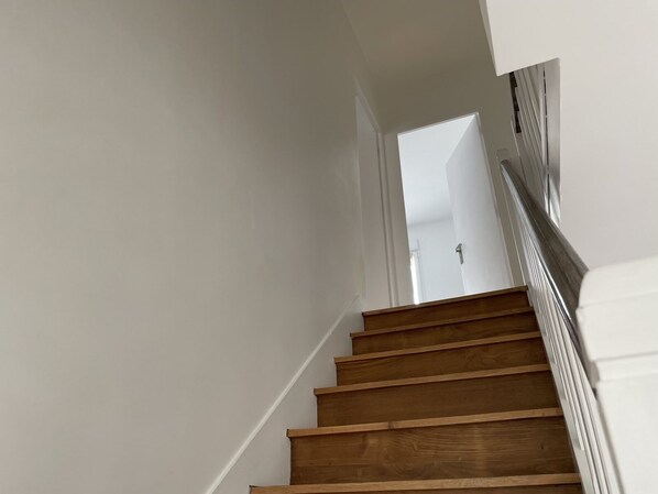 A wooden staircase with white walls and a door at the top.