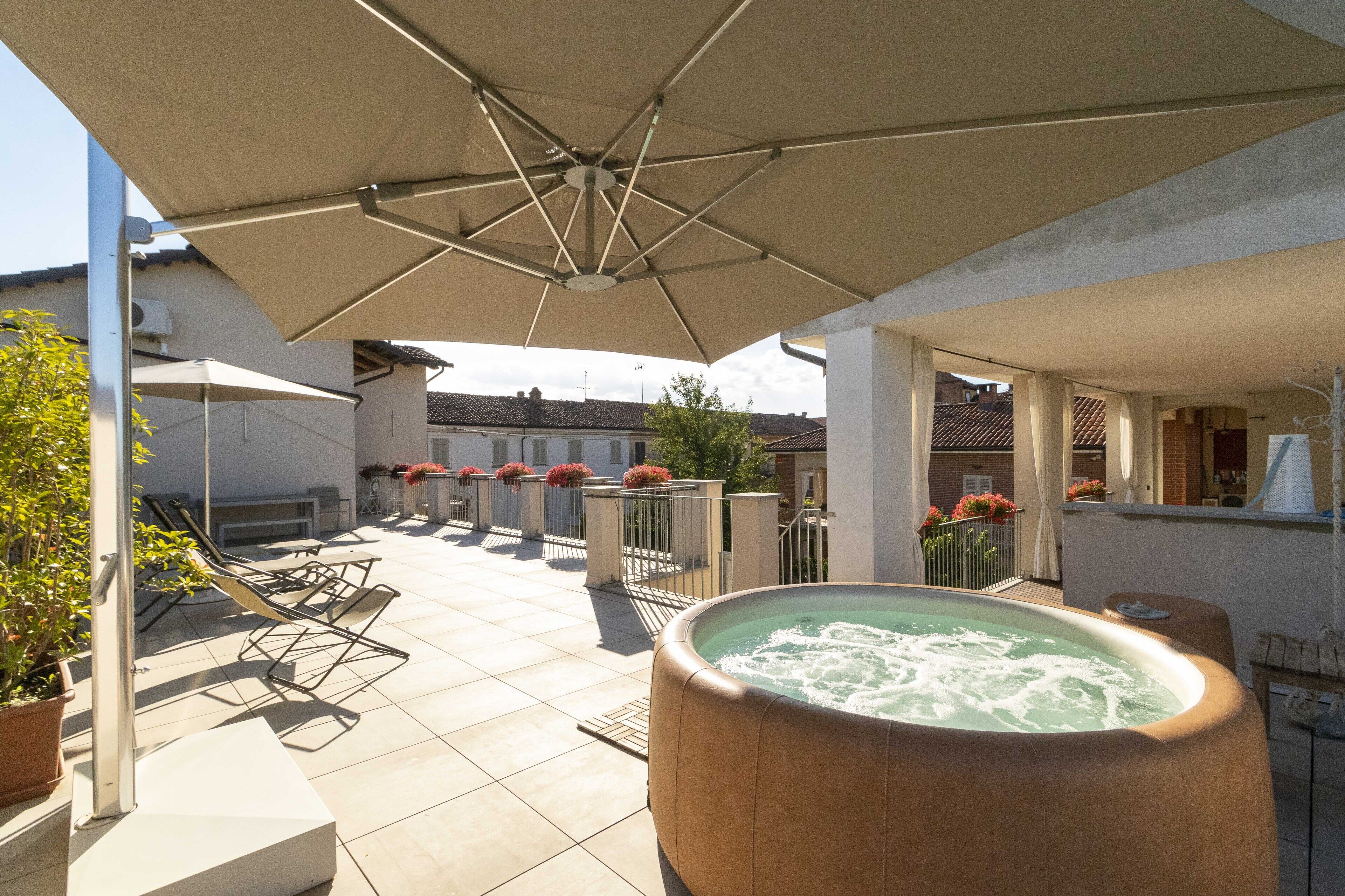 A rooftop patio with a hot tub, sun loungers, and umbrellas.