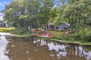 Una proprietà sul lago con un molo, sedie rosse e un gazebo.