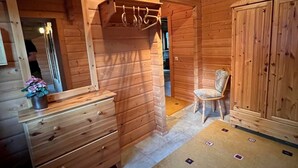 A wooden cabin interior with a wooden dresser, a mirror, a chair, and a cabinet. - Ferienwohnung im Holzhaus, 5-10 Min. vom Schönen Wandlitzsee Entfernt (Wandlitz)