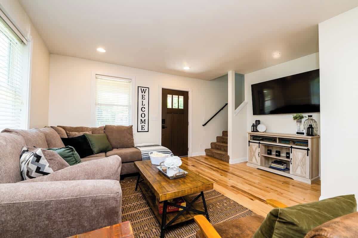 A modern living room with a sofa, coffee table, and a TV mounted on the wall.