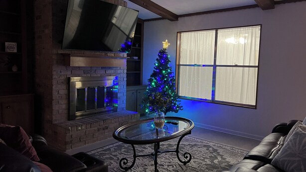A cozy living room with a fireplace, a Christmas tree, and a large window. - Cozy, spacious & convenient home-3bedrooms 3baths (Pasadena)