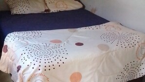 A small, single-bed room with a plain wall and a tiled floor. - Garden Guest House Bed & Bre Chitungwiza (Harare)