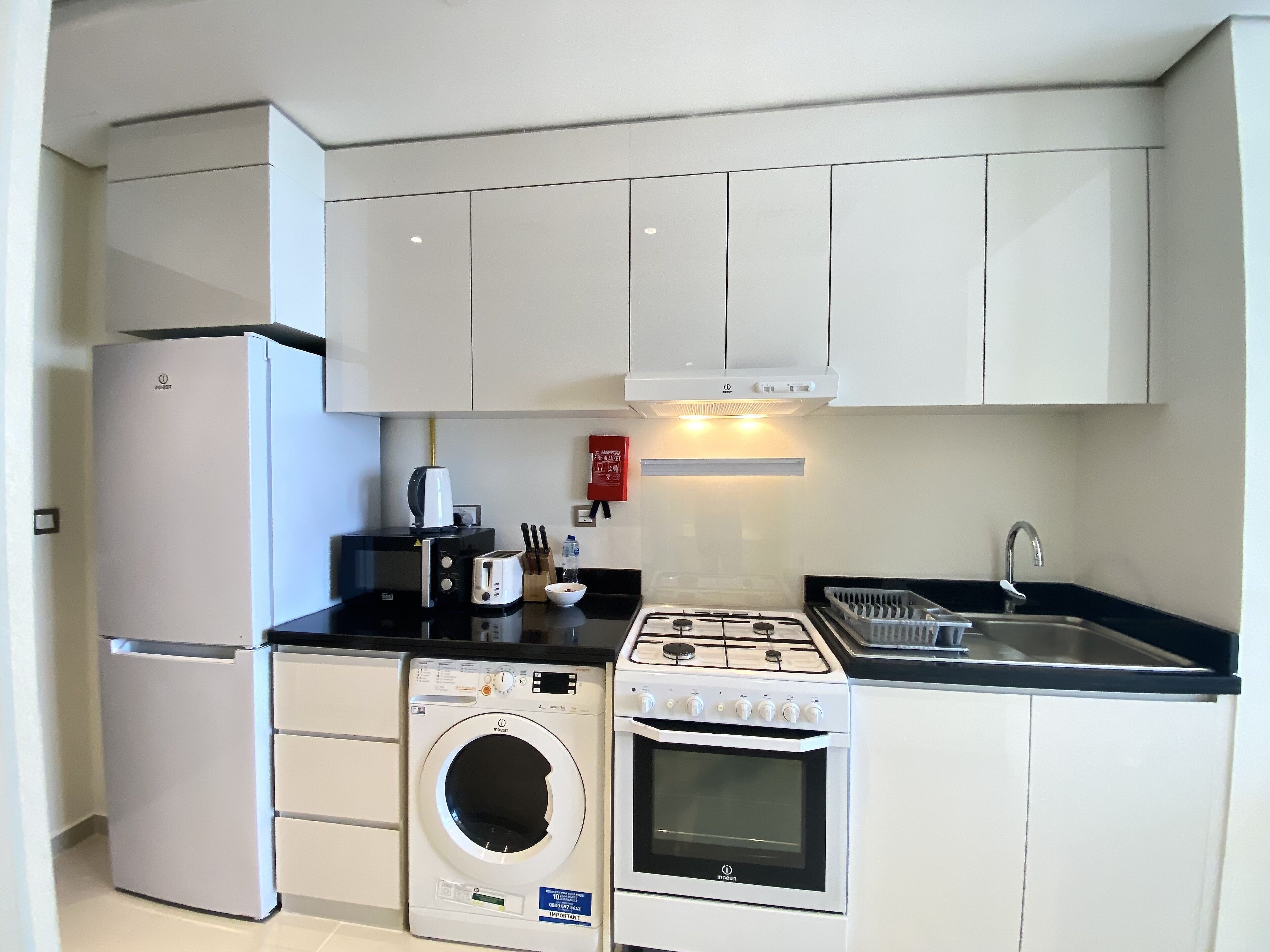 A compact kitchen with a built-in washer, oven, and a gas stove.