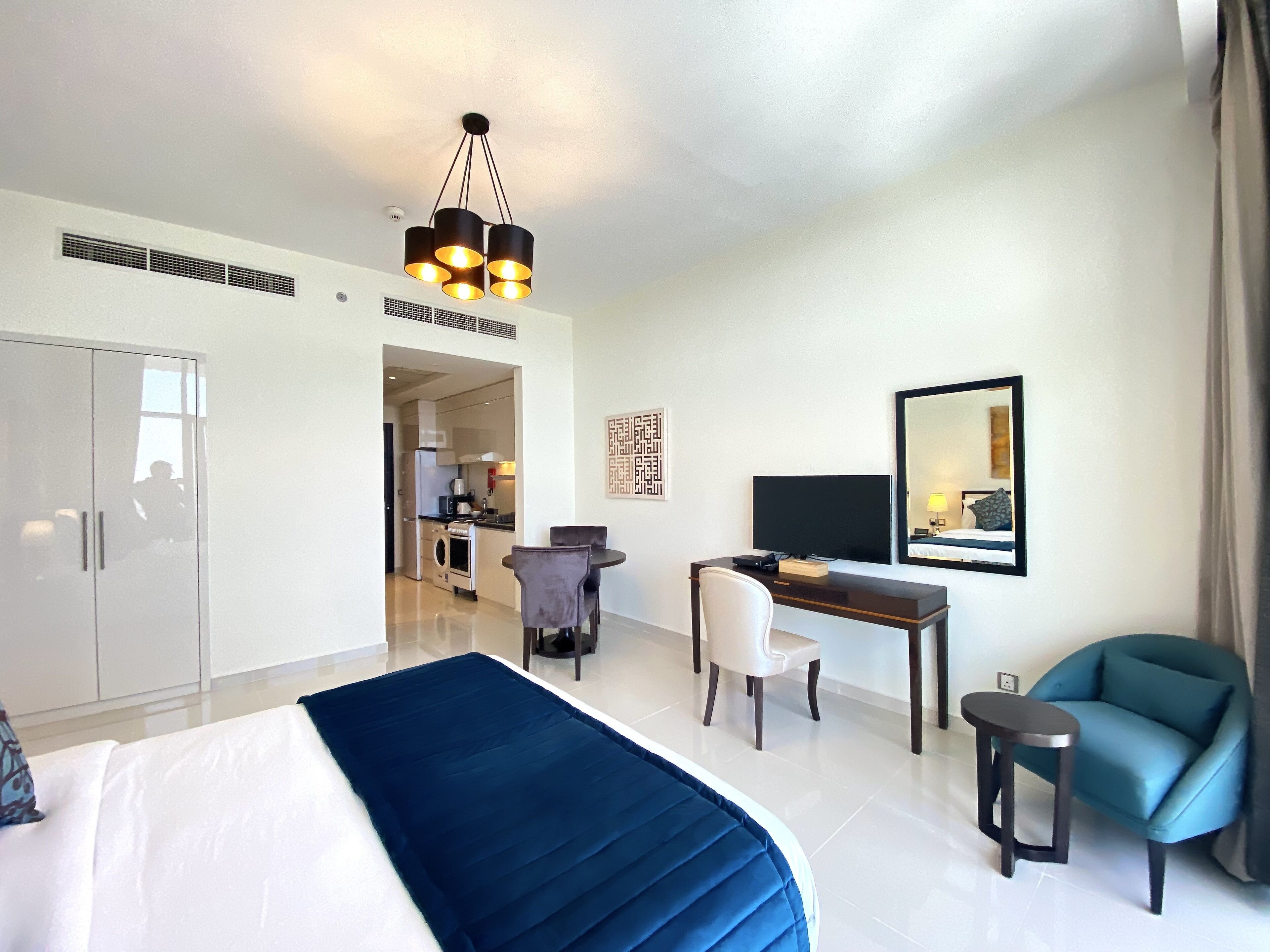 A hotel room with a bed, a desk, a chair, a TV, and a mirror.