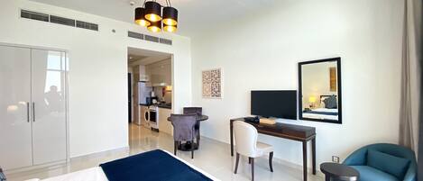 A hotel room with a bed, a desk, a chair, a TV, and a mirror.