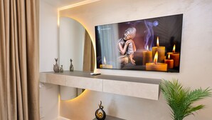 Ein modernes Wohnzimmer mit einem an der Wand montierten Flachbildfernseher, einem kleinen Topfpflanzen und einer dekorativen Vase auf einer Konsolentisch.