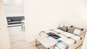 Une chambre à coucher moderne avec un lit, un banc et un canapé à l’arrière-plan.