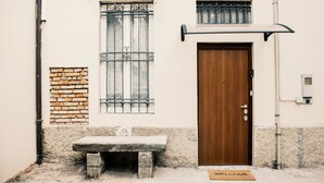 Un bâtiment avec une porte en bois, un banc et un paillasson.