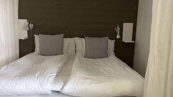 A bed with a dark headboard, white bedding, and two bedside lamps.
