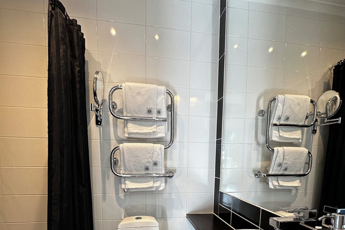 A modern bathroom with a toilet, sink, and towel racks.