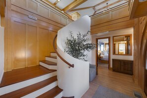 Stunning staircase leads to a spacious room with a large mirror, bed, and nightstand.