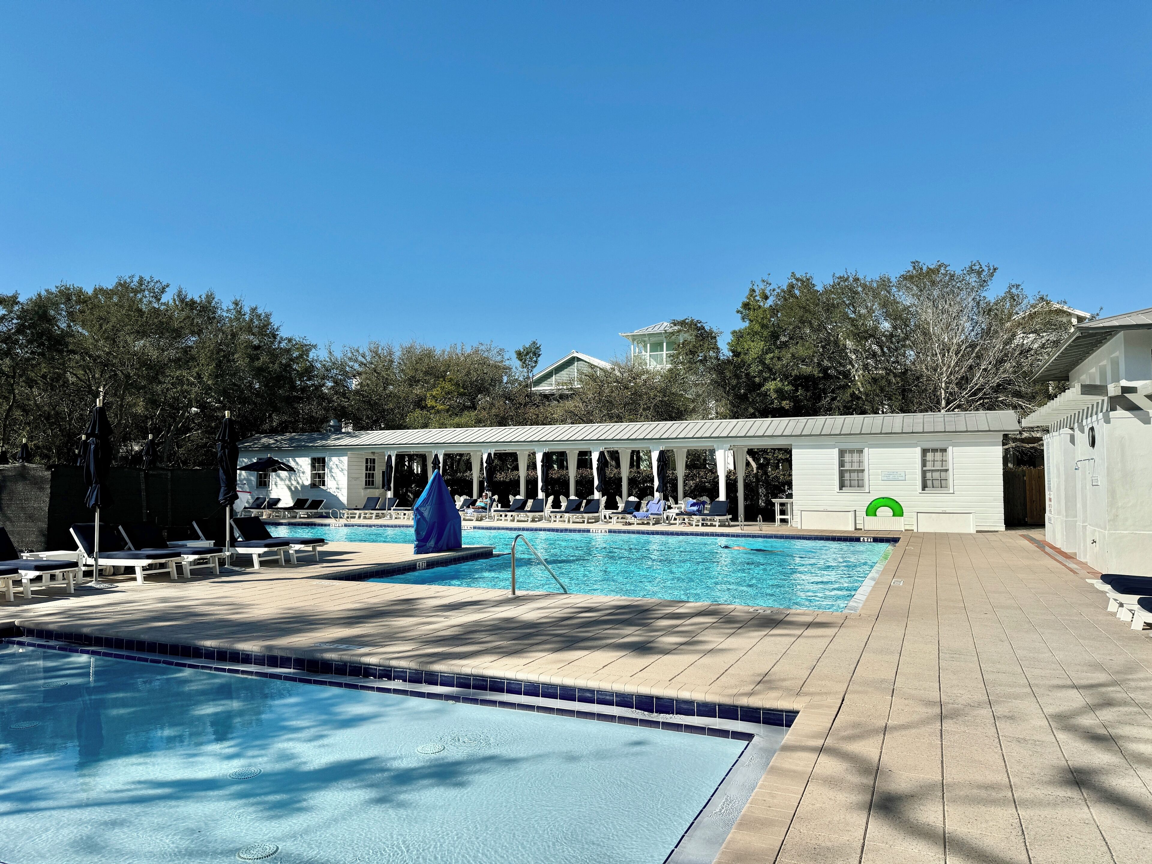 A pool area with lounge chairs and a covered seating area.
