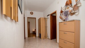 Un couloir avec une armoire en bois, une porte décorée d’une étoile de mer et un mur orné d’un filet et d’étoiles de mer.
