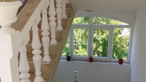 Un escalier avec des balustrades blanches menant à un palier doté d’une fenêtre donnant sur un espace verdoyant.