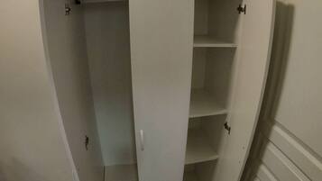 A white walk-in closet with multiple shelves and a small compartment.