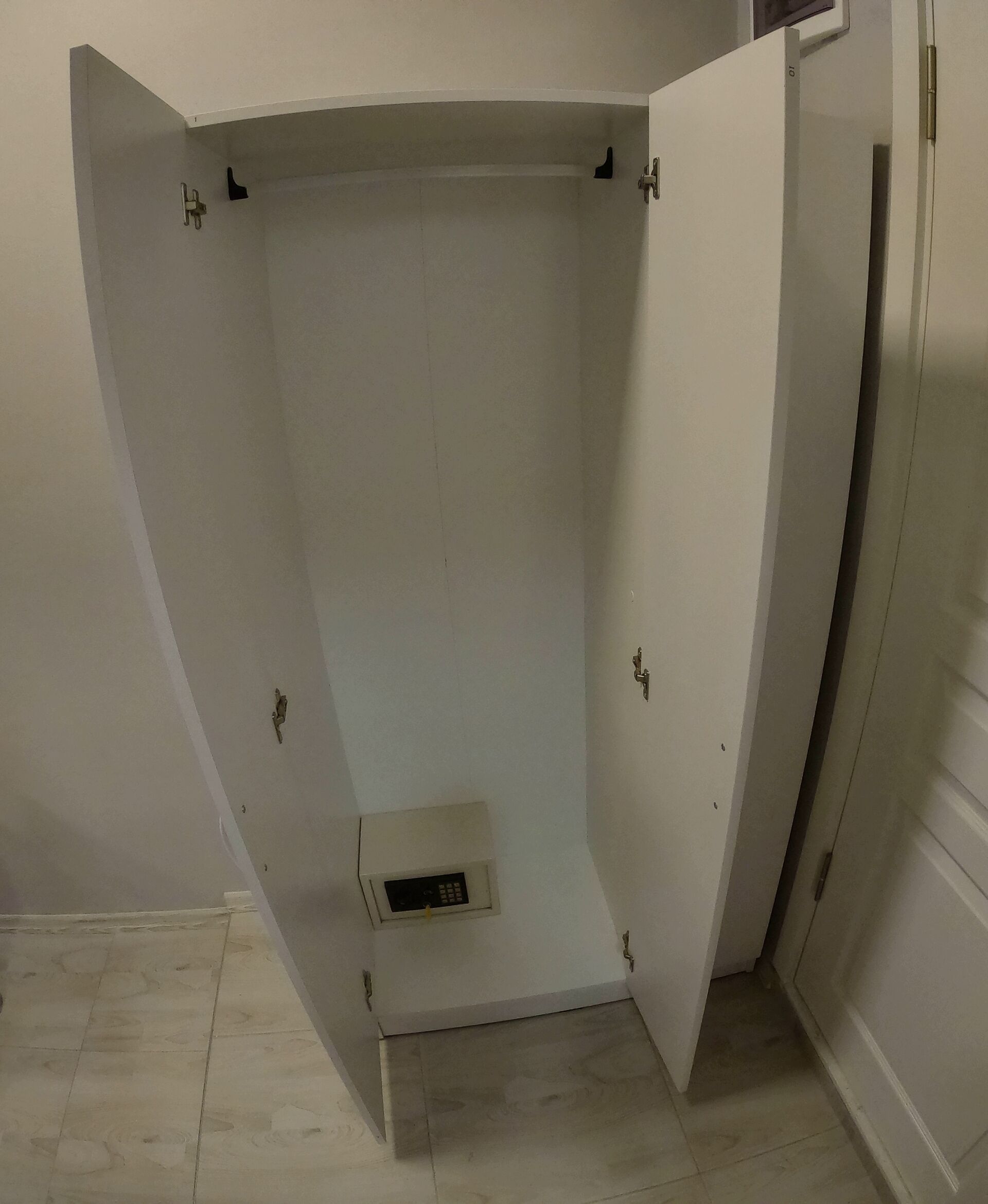 Een kamer met douche, een deur en een kleine ventilatieunit aan de muur.