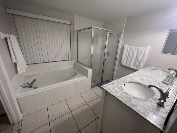 Un baño moderno con bañera, cabina de ducha de vidrio y lavamanos con encimera de mármol.