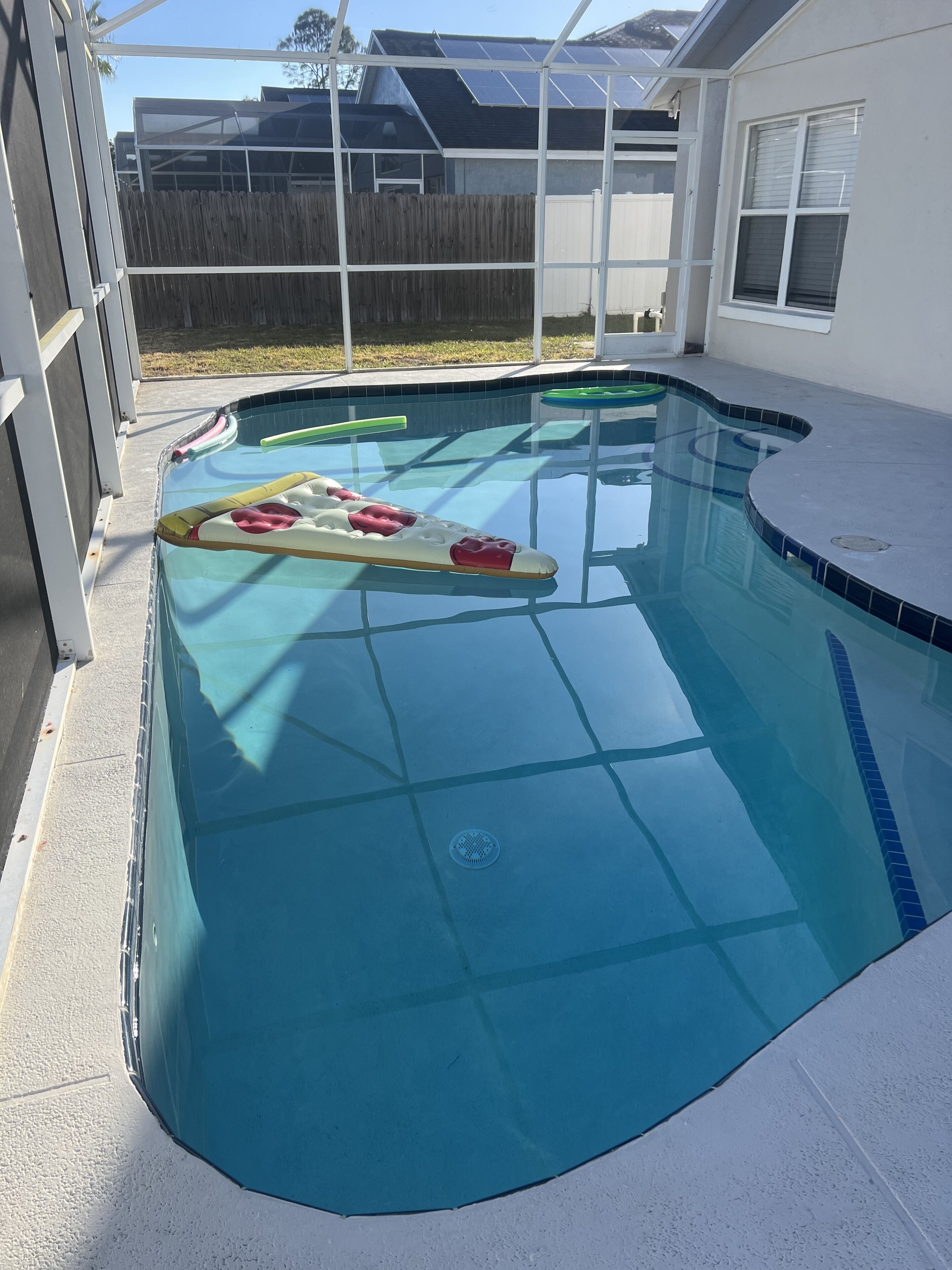A swimming pool with a wooden deck and a covered area.