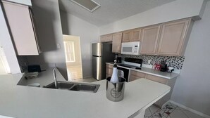 A modern kitchen with a central island, stainless steel appliances, and a tiled backsplash. - Beautiful house just 12min from Disney World! (Kissimmee)