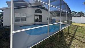 A house with a swimming pool, a covered patio, and a fenced backyard. - Beautiful house just 12min from Disney World! (Kissimmee)