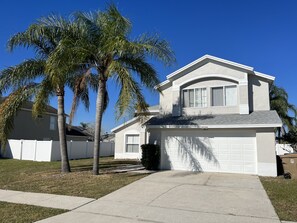 Een tweelaags huis met garage, gazon en een palmbom.