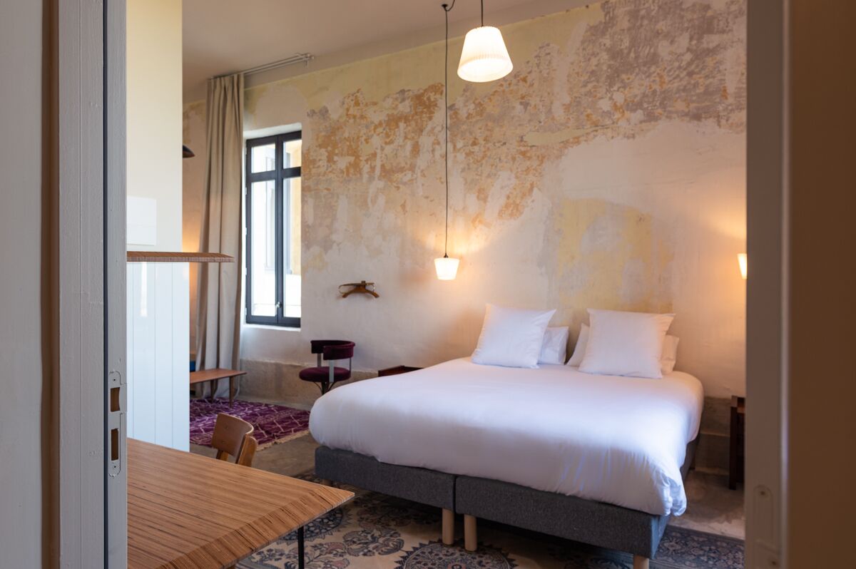 A bedroom with a large bed, a wooden table, and a patterned rug.