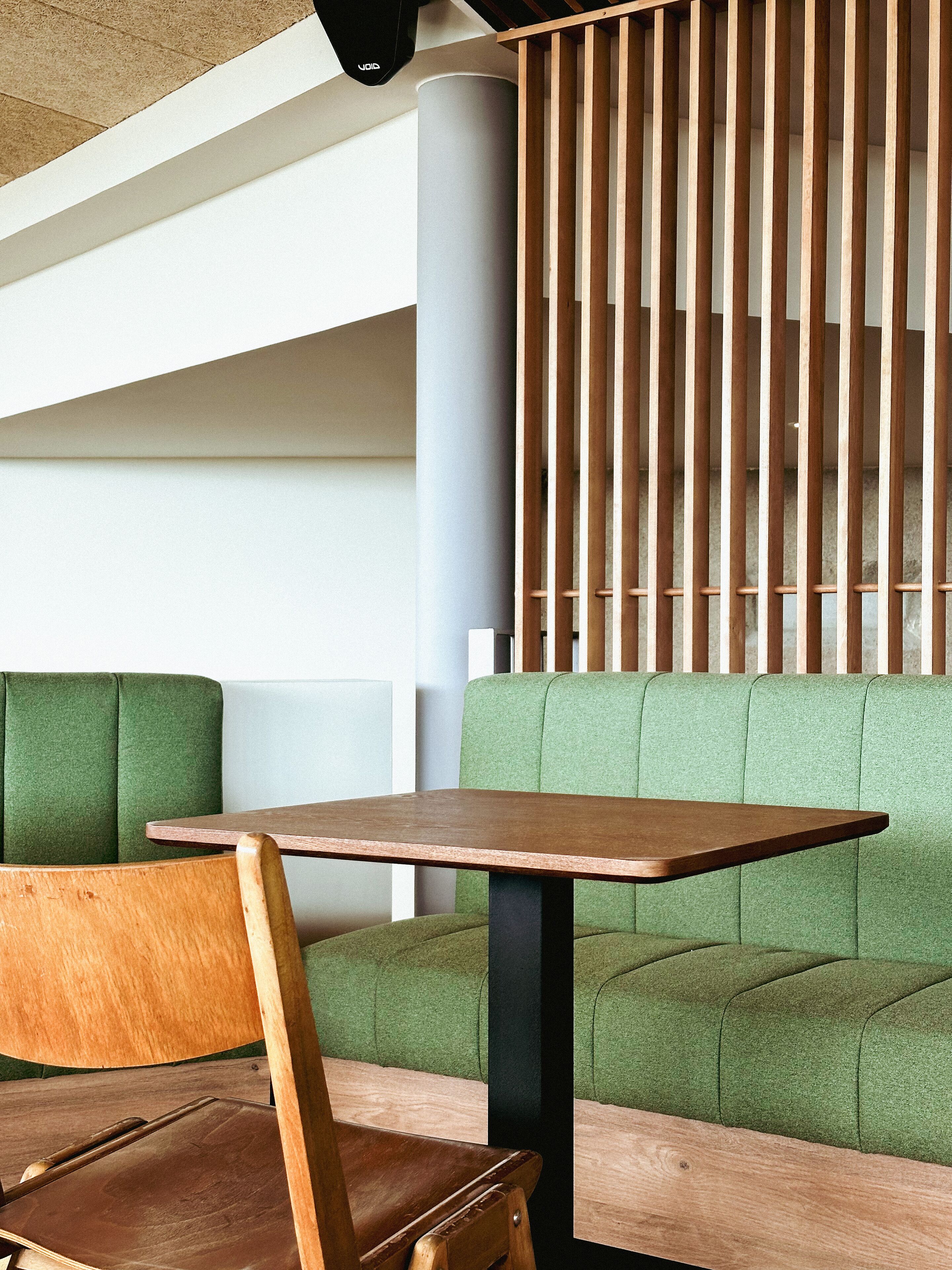 Un interno moderno con un tavolo in legno e sedute rivestite di verde.
