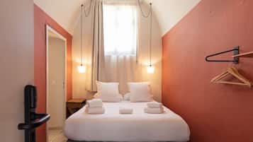 Een hotelkamer met een bed, nachtkastjes, een hanglamp en een kapstok.