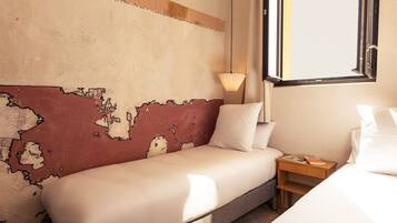 A hotel room with a large bed, a nightstand with a lamp, and a wall with a map design.