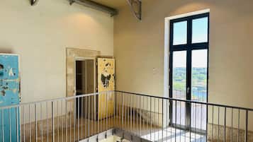 Un interior espacioso con balcón, un ventanal con vistas y una puerta que da a otra habitación.