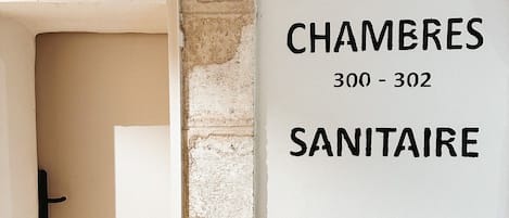 A sign indicating the direction to the 'Chambres' (Rooms) and 'Sanitaire' (Bathroom) on floors 300 to 302.