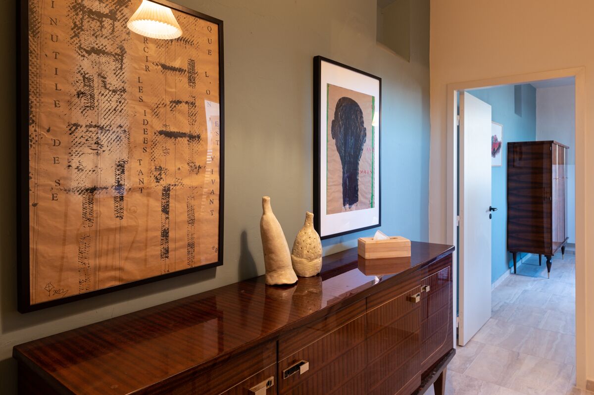 A wooden console table with a framed abstract artwork and two vases.