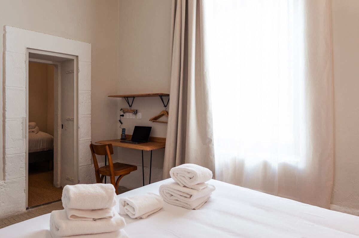 Una habitación de hotel con cama, escritorio, silla y ordenador portátil.