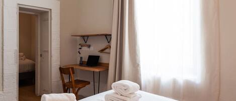 Una habitación de hotel con cama, escritorio, silla y ordenador portátil.