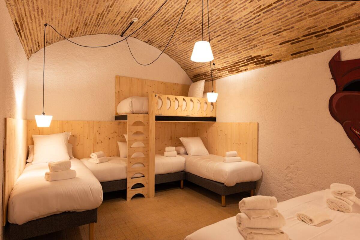 A cozy room with bunk beds, a wooden ladder, and two bedside tables with towels.