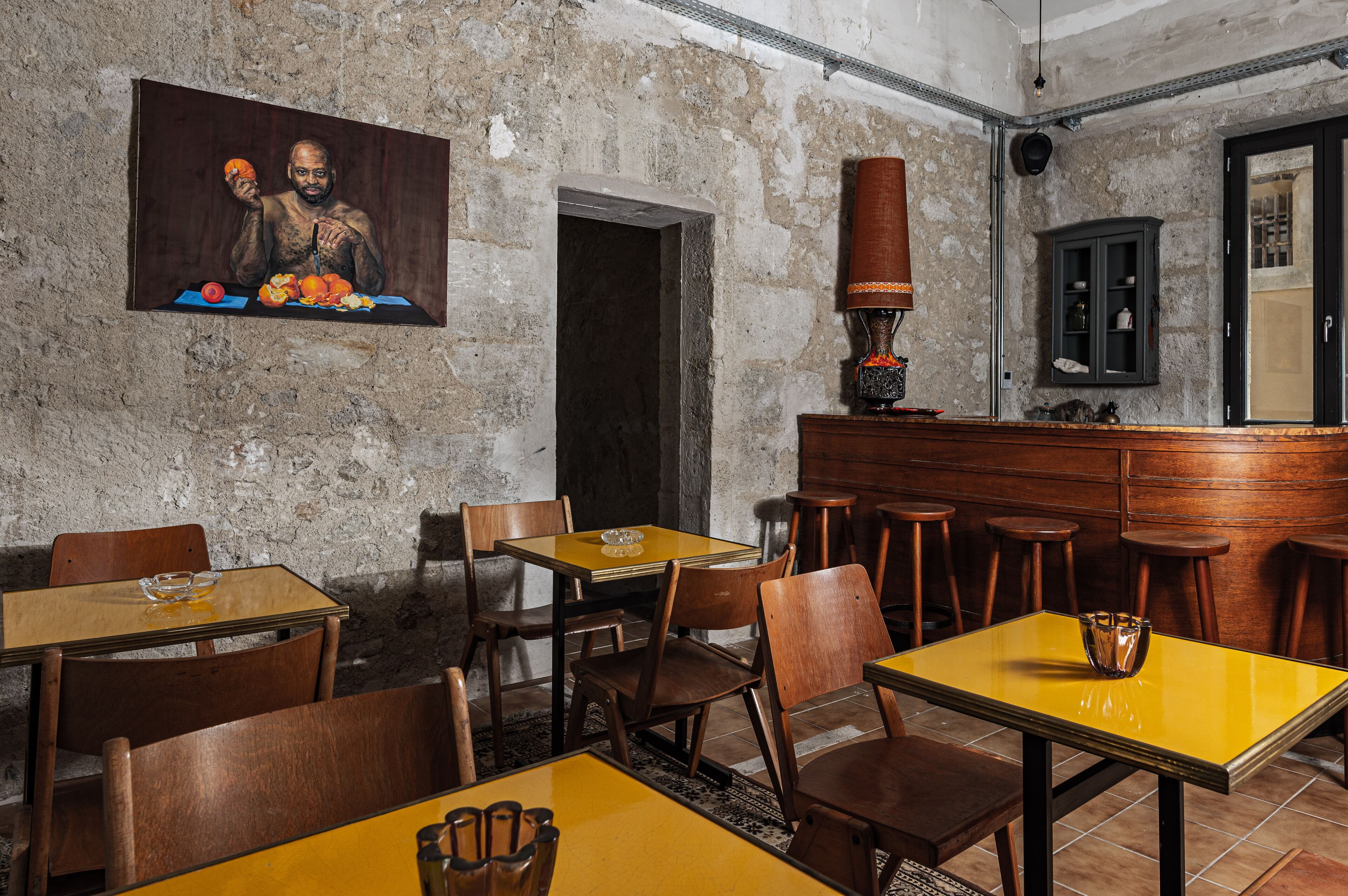 Un restaurante con mesas y sillas de madera, una zona de bar y una pared de piedra.