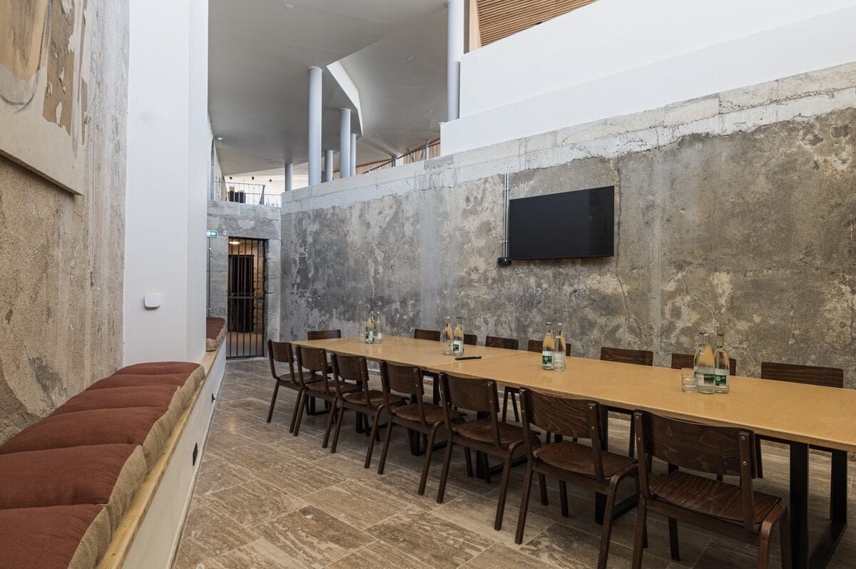 Un salón de conferencias con una mesa larga, sillas de madera y un televisor de pantalla plana montado en la pared.