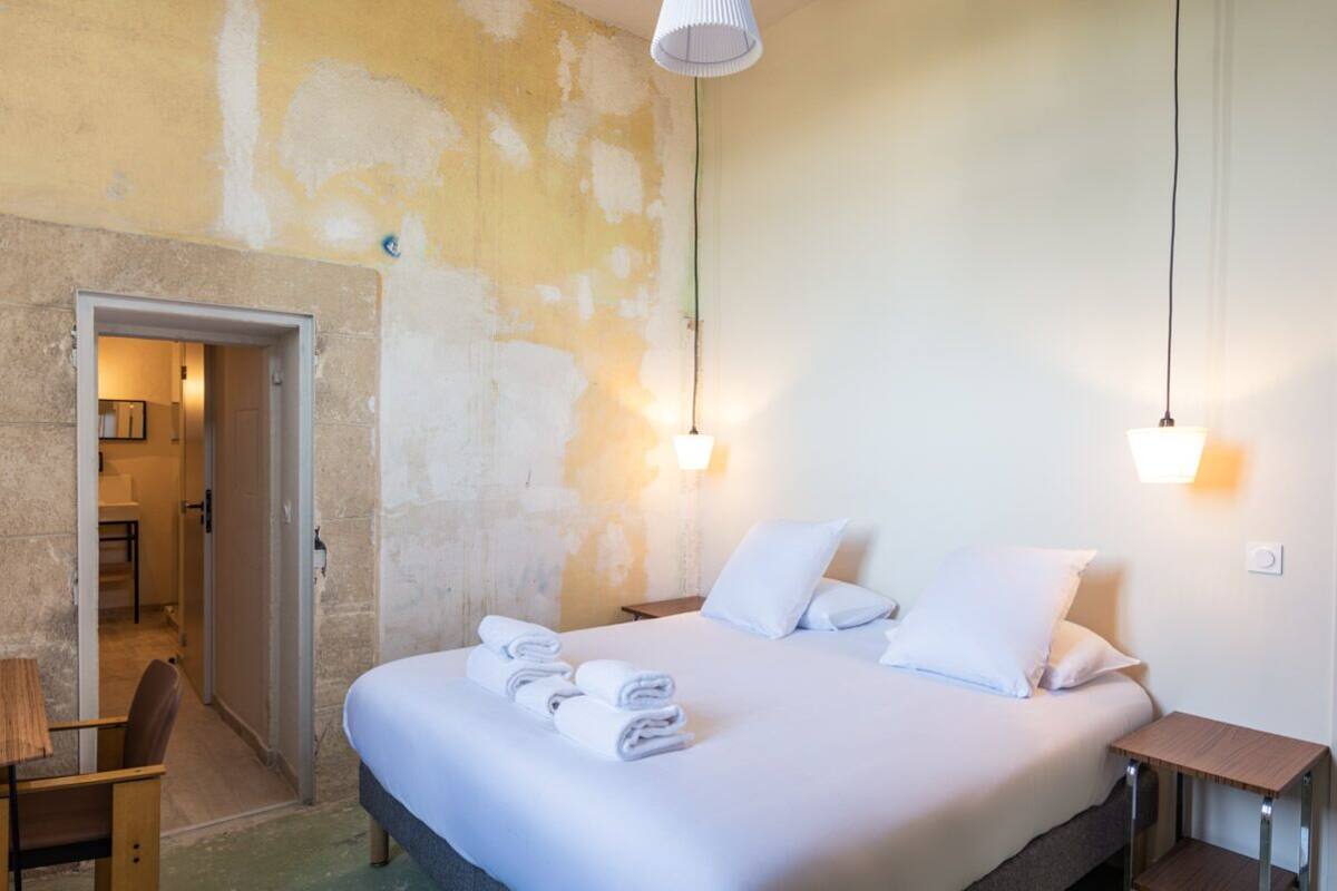 A hotel room with a bed, bedside tables, and a door leading to a bathroom.