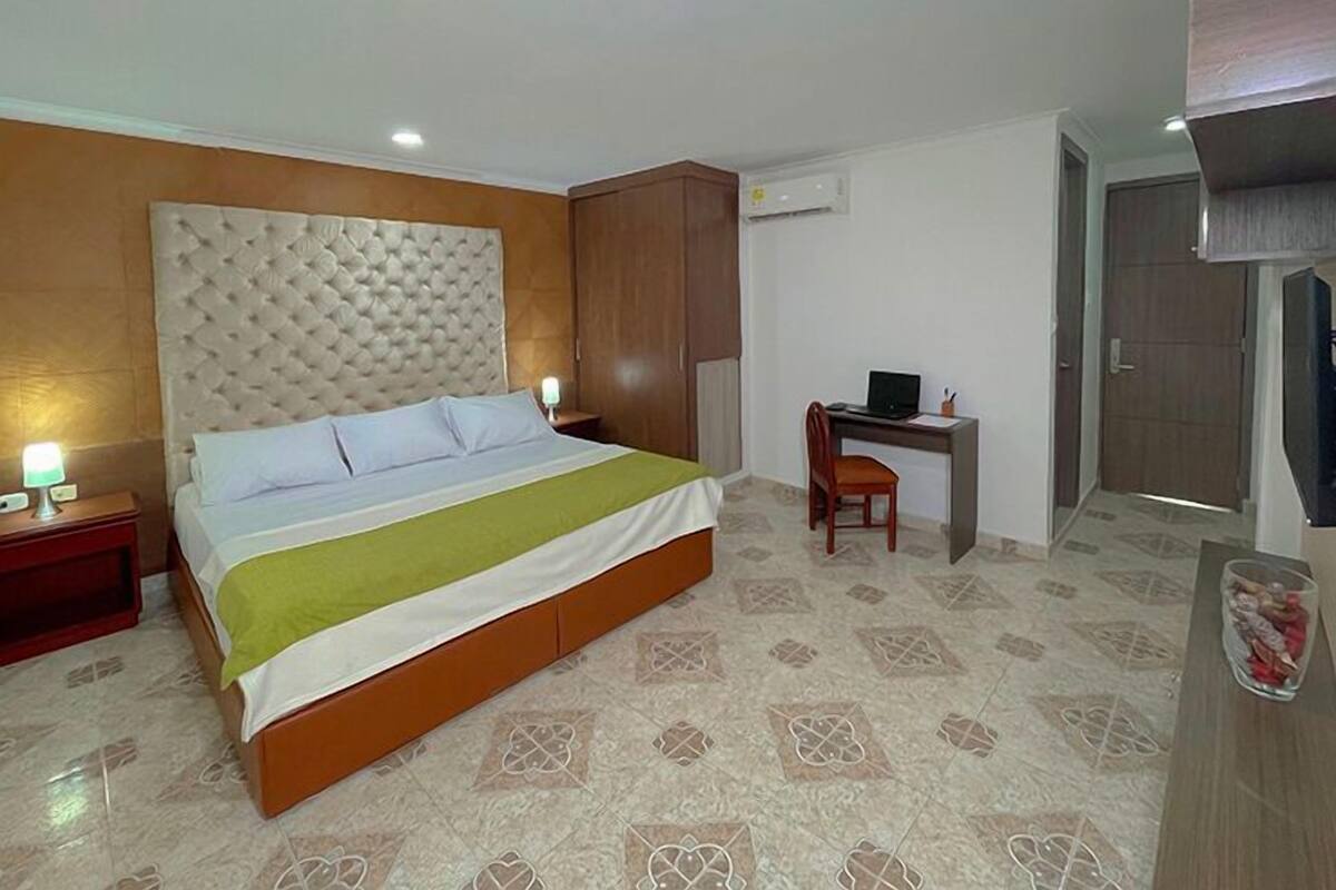 A hotel room with a bed, a desk, and a wardrobe.