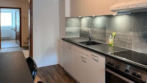 Cozinha moderna com uma pia de aço inoxidável, forno embutido e janela com vista para a sala de estar.