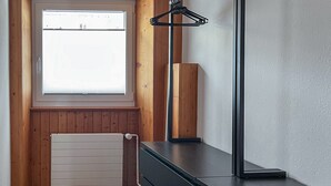 Quarto moderno com painel de madeira, janela, radiador e escrivaninha preta com abajur.