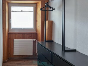 Une chambre moderne avec un mur lambrissé en bois, une fenêtre, un radiateur et un bureau noir avec une lampe.