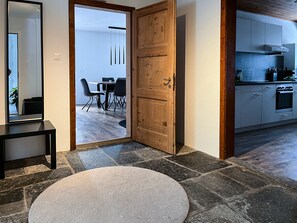 A modern kitchen with white cabinets, a built-in oven, and a dining area with a table and chairs. - Beautiful, sunny ground floor apartment with 3 rooms and garden (Poschiavo)