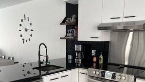 Una cocina moderna con armarios blancos, un lavavajillas de acero inoxidable, un horno empotrado y un salpicadero negro.