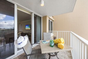 A balcony with a table, a chair, a hat, bottles, and a TV in the background.